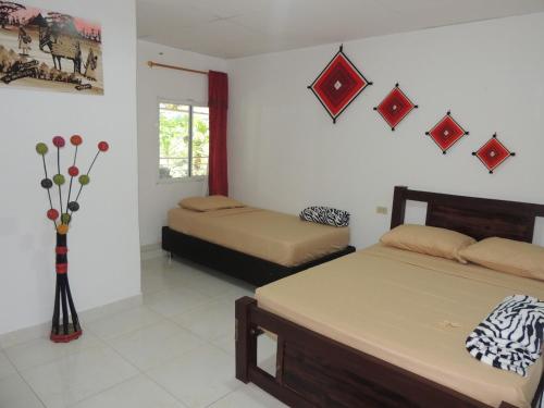 a bedroom with two beds and a vase with flowers at Hostal Alto de la Montaña in Minca