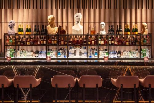 a bar with several mannequins behind a counter with bottles of alcohol at The Londoner in London