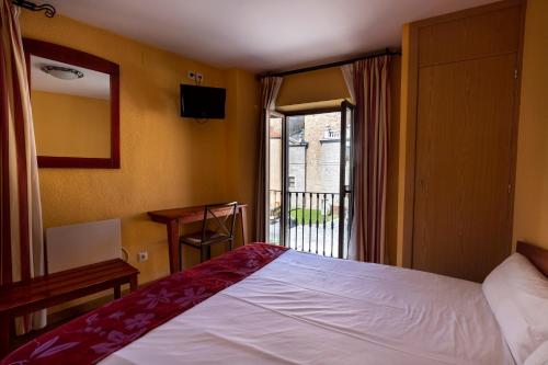 Habitación de hotel con cama y ventana en Hostal Restaurante Puerta del Alcázar, en Ávila