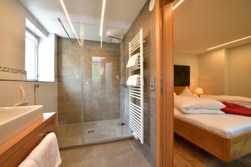 a bathroom with a shower and a bed and a sink at Landhaus Thaler in Mittelberg
