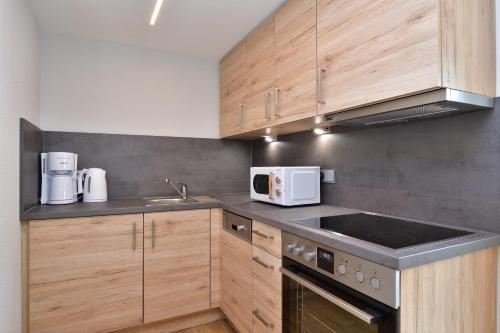 a kitchen with wooden cabinets and a sink and a microwave at Landhaus Thaler in Mittelberg