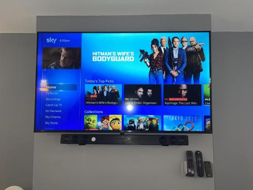 a flat screen tv hanging on a wall at NEW Luxurious Modern Large 3 Bed House - Sleeps Up to 10 Guests - Sky Ultra HD, Sky Movies, Netflix, Disney Plus in Mansfield