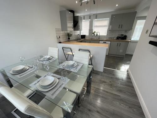 a dining room with a glass table and chairs at NEW Luxurious Modern Large 3 Bed House - Sleeps Up to 10 Guests - Sky Ultra HD, Sky Movies, Netflix, Disney Plus in Mansfield