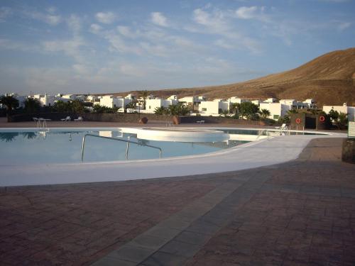 une grande piscine avec des bâtiments en arrière-plan dans l'établissement Villa Nicole, à Playa Blanca
