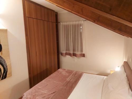 1 dormitorio con 1 cama con cabecero de madera y ventana en Apartments Villa Aurora, en Ražanac