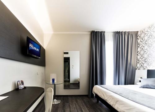 Habitación de hotel con cama, escritorio y TV. en Ilga Hotel, en Collecchio