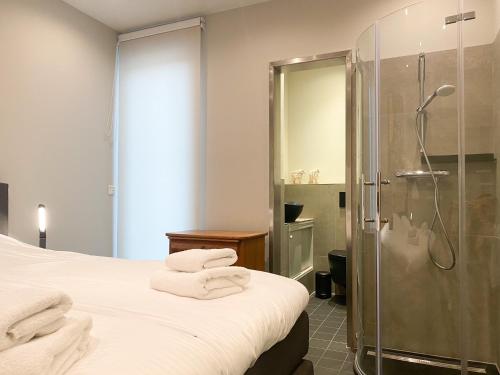 a bedroom with a shower and a bed with towels at Studio KA06 Het Strandhuis in Vlissingen