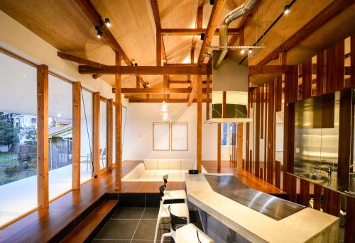 Großes Zimmer mit Holzdecken sowie einem Tisch und Stühlen. in der Unterkunft Wellis Villa HANARE in Awaji