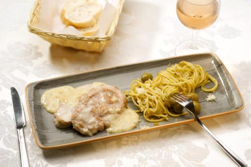 a plate of food with pasta and a fork and a glass of wine at Panorama Hotel Lohme in Lohme