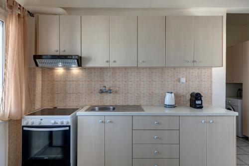 a kitchen with white cabinets and a stove top oven at Ven al Mar in Azolimnos