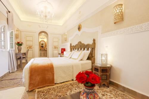 a bedroom with a bed and a vase with red flowers at Riad Palais Des Princesses & Spa in Marrakesh