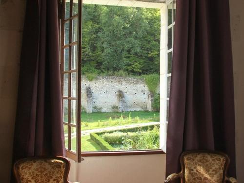 een raam met 2 stoelen en uitzicht op een tuin bij Chateau-monastère de La Corroirie in Montrésor