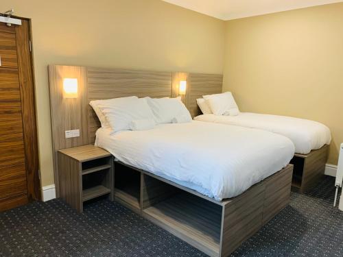 a bedroom with two beds with white sheets at De Regency Style Hotel in Redditch