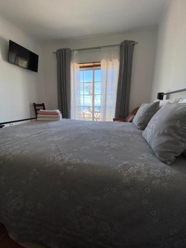 a bedroom with a large bed with a window at Vina's Place in Nazaré