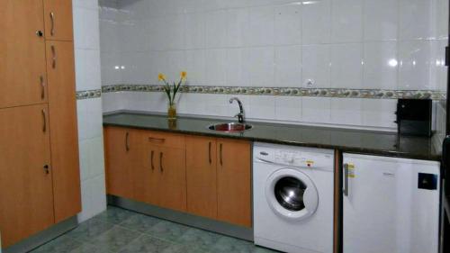 uma cozinha com uma máquina de lavar roupa e um lavatório em Albergue Buen Camino em Navarrete