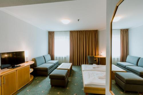 a hotel room with a couch and a television at Prachárna Park Hotel Olomouc in Olomouc