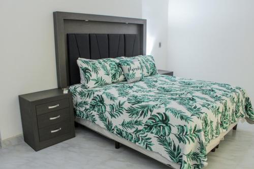 1 cama con manta verde y blanca y mesita de noche en VILLA COSTA FELIX 1 en Puerto Peñasco