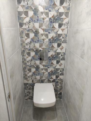 a bathroom with a toilet and a tiled wall at Victoria in Tiraspol