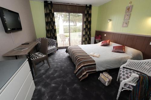 a hotel room with a bed and a desk and a television at L'Hippocampe in Plouharnel