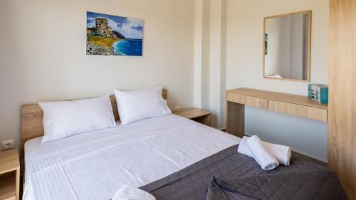a bedroom with a bed with white sheets and a mirror at Mythic Villas in Epanomi
