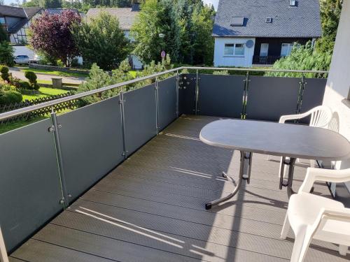 a deck with a table and chairs on a balcony at Ferienwohnung Schanzenblick in Winterberg