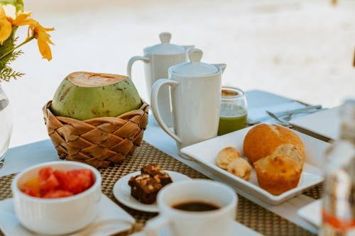 a table with a plate of food and cups of coffee at Casa na Praia in Jericoacoara