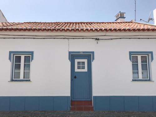 a white house with a blue door and two windows at Casa Campinho in Campinho