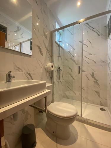 a bathroom with a toilet and a shower and a sink at Vina's Place in Nazaré