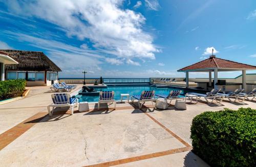 a pool with lounge chairs and the ocean in the background at Hotel & Museo Casa Turquesa in Cancún