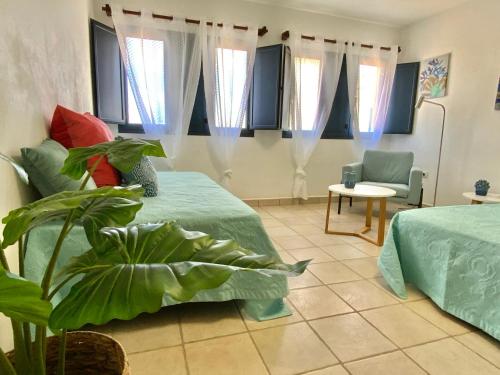 um quarto com 2 camas, uma cadeira e janelas em Maresia Holiday House em Caleta de Sebo
