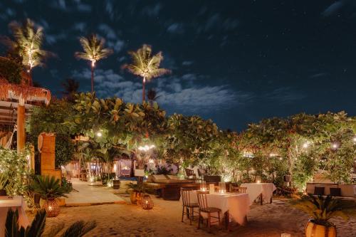 a restaurant with tables and chairs and palm trees at night at Casa na Praia in Jericoacoara