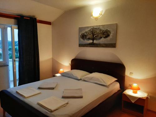 a bedroom with a bed with a tree on the wall at Apartments Donadic I, Caska in Novalja