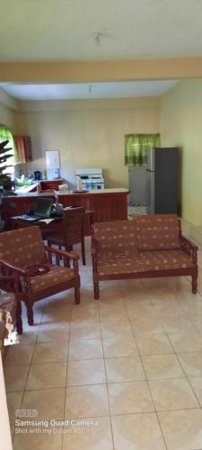 a living room with two benches and a kitchen at 3 Bedroom Apartment in westerrn Tobago in Maryʼs Hill