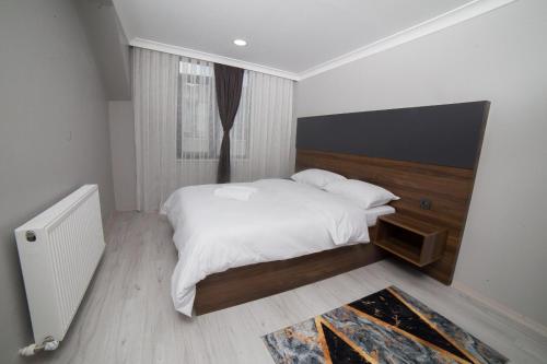 Schlafzimmer mit einem weißen Bett mit einem Kopfteil aus Holz in der Unterkunft Alya Hotel in Istanbul