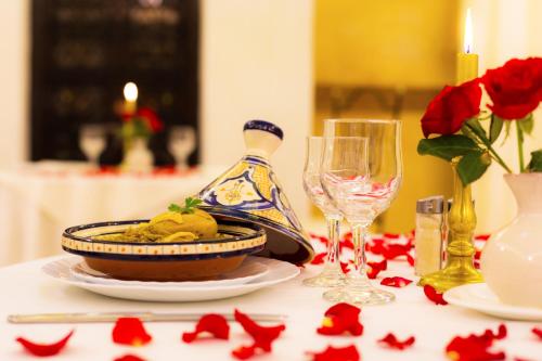 a table with a plate of food and wine glasses at Riad Palais Des Princesses & Spa in Marrakesh
