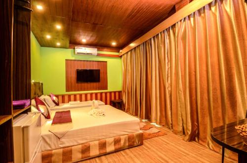 a hotel room with a bed and a tv at Summer Villa Guest House in Maafushi