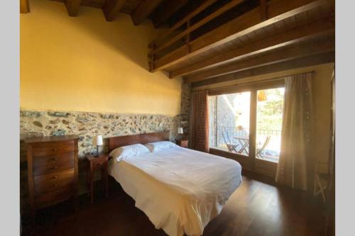 1 dormitorio con cama y ventana grande en Cal Masover, casa de piedra rehabilitada, en Planoles