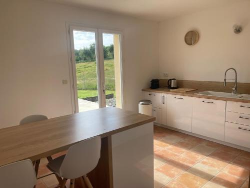 une cuisine avec des armoires blanches et une table avec des chaises dans l'établissement La Prairie Vagabonde, à Surville