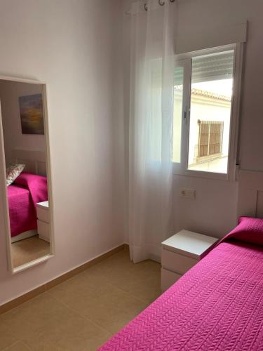 a bedroom with a pink bed and a mirror at Apartamento Playa de la Guardia in Salobreña