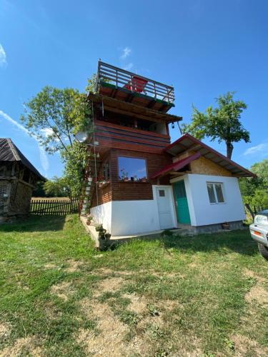 uma casa com uma varanda em cima em Cabana Tinca em Corbeni