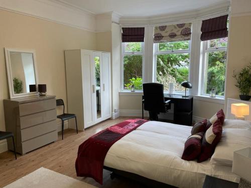 a bedroom with a bed and a desk and windows at Lade Braes 3 Bed Apartment Central St Andrews in St Andrews
