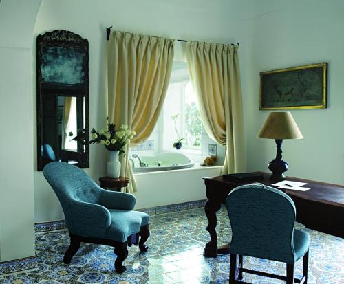 a room with two chairs and a desk and a tub at Le Sirenuse in Positano