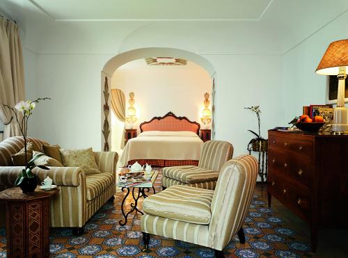 a bedroom with a bed and a couch and chairs at Le Sirenuse in Positano