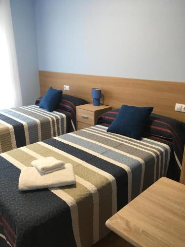 duas camas num quarto de hotel com toalhas em Pensión Santirso em Palas de Rei