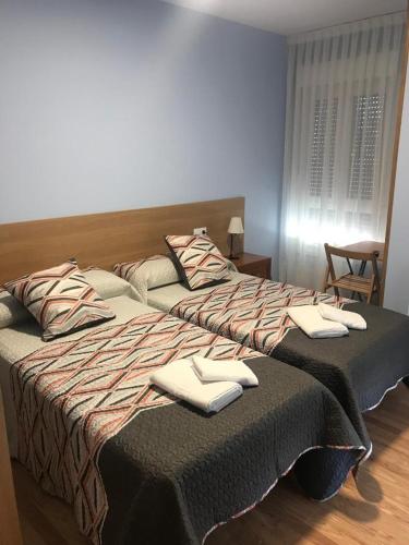 two beds in a hotel room with towels on them at Pensión Santirso in Palas de Rei 