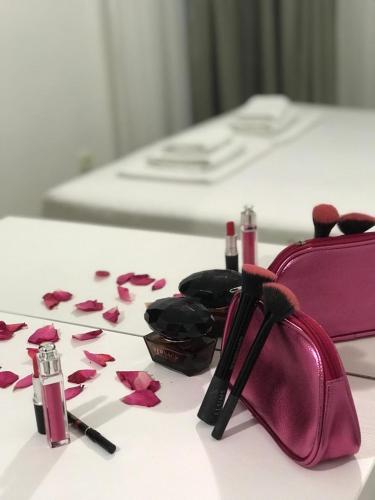 a pink purse and pink petals on a bed at Apartmani Matković in Sutomore
