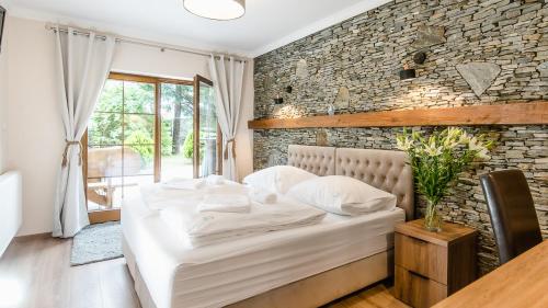 um quarto com uma cama branca e uma parede de tijolos em Apartamenty Kapitańskie em Olawa