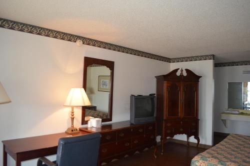 a hotel room with a bed and a desk and a television at Granbury Inn and Suites in Granbury