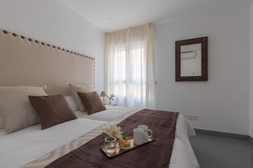 Un dormitorio con una cama con una bandeja de comida. en Living4Malaga Juan de Austria, en Málaga