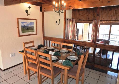 a dining room with a wooden table and chairs at Fairways Holiday Accommodation in Drakensberg Garden